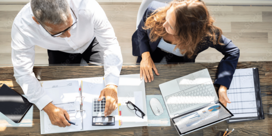 Man and Woman sitting at a desk together looking at spreadsheets